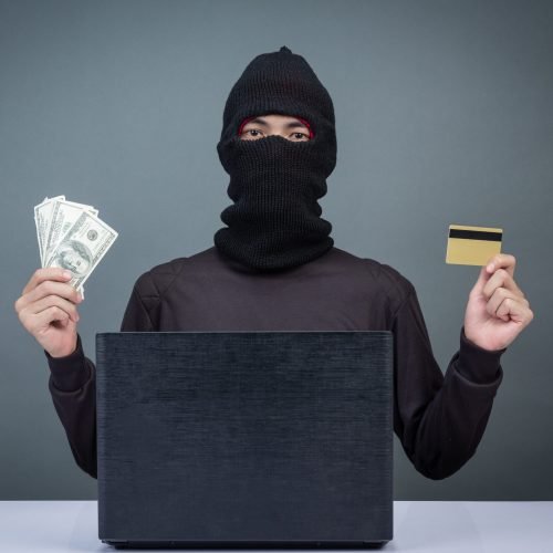 Thieves hold credit cards using a laptop computer for password hacking activities. Cyber crime concepts